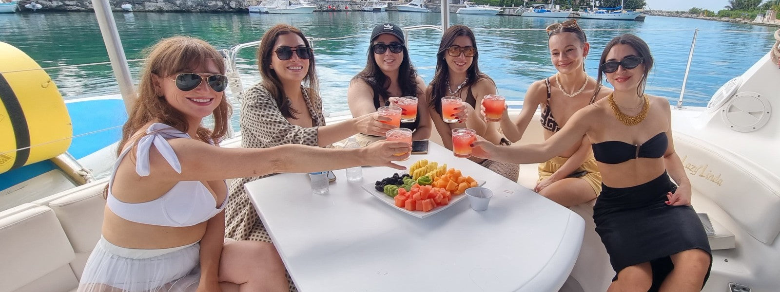 Group of women toasting with cocktails and enjoying fresh fruit during a private yacht charter with Beyond the Experience in Riviera Maya